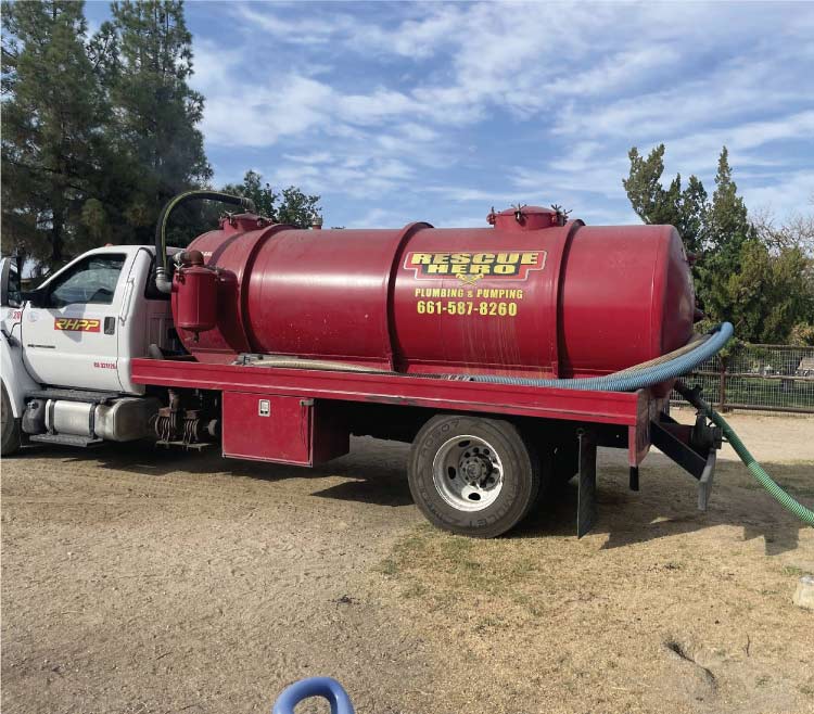 A licensed plumber using equipment to clean a residential septic tank in Bakersfield, CA.