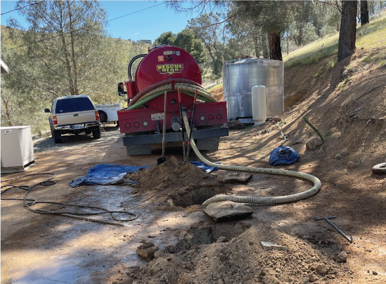 Red Rescue Hero Plumbing truck pumping a residential septic tank through a dug-out access point, showing the necessary equipment for septic tank pumping and service.