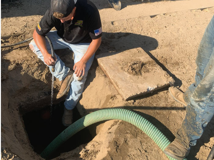 Professional plumber inspecting the septic tank baffle and inlet lines during a routine pumping service.