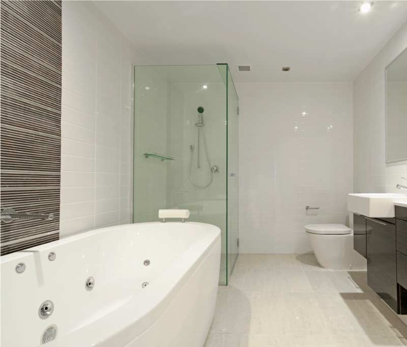 Elegant modern bathroom renovation featuring a large white soaking tub, glass-enclosed walk-in shower, and contemporary fixtures, for a toilet installation by professional plumbers.