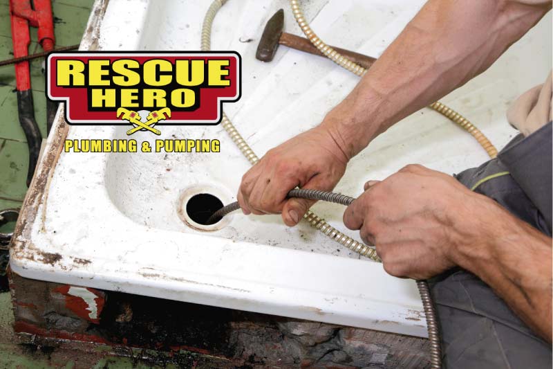 Close-up of a Rescue Hero Plumbing technician using a professional motorized drain snake to clear a clogged shower drain in a Bakersfield home.