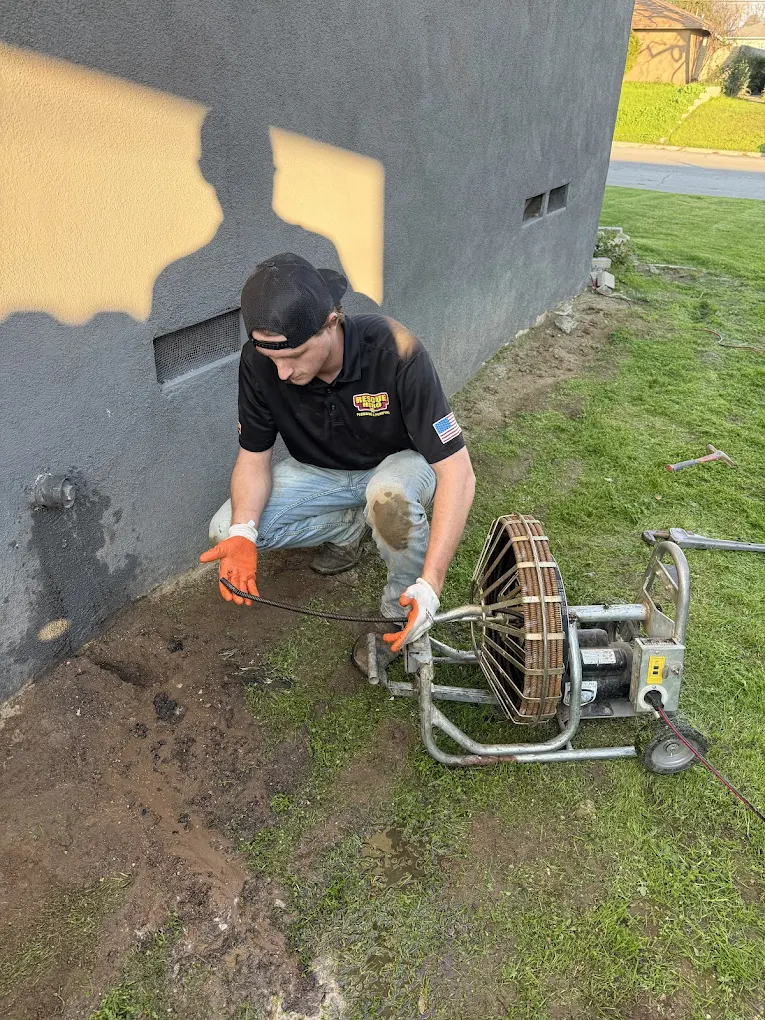 Expert technician in uniform inspecting a copper water heater pressure relief valve assembly.