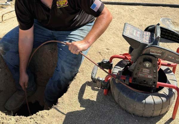 Professional plumber in Wofford Heights using a RIDGID SeeSnake video camera for a precise sewer line inspection to identify blockages or pipe damage.