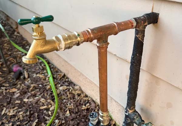 Newly installed copper pipe plumbing manifold with brass sweat fittings and shutoff valves for residential water lines.